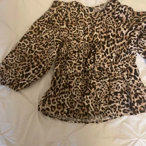 Leopard blus med knyt - En fin blus där man knyter ihop den med tre separata rosetter på framsidan. Den är i leopard och endast använd max 4 ggr. 🐆 Har resår i ärmarna och de är inte fullt långa. Passar xs men också s och m. Hör av dig med frågor!