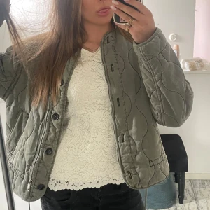 Vit spetsblus med kort ärm - Säljer en söt vit blus i spets med korta ärmar. Blusen har en rak passform och vackert spetsmönster över hela plagget. Perfekt att styla med jeans eller kjol för en fräsch look.