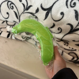 Grön bananformad leksak Bananfodral Bananhållare för utomhusbruk - En rolig, grön leksak i form av en banan. Perfekt för lek och skoj! Bananhållare för utomhusbruk, resor och förvaring. Sött skydd för din banan. Skydda din banan nu! 