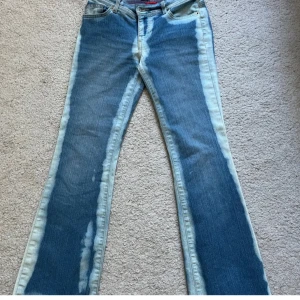 Blå bootcut jeans med blekta detaljer - Unika blå jeans med bootcut passform och tydliga blekta partier längs benen. Klassisk femficksmodell med normalhög midja och dragkedja. Jeansen har en cool vintagekänsla och är perfekta för dig som vill sticka ut. Köpte på Plick men tyvärr för små då ja är runt 175 cm! Passar perfekt för dig som är runt 167💕💕