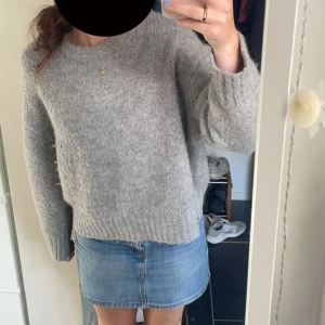 Grå stickad tröja från Zara - Säljer en mysig grå stickad tröja från Zara. Tröjan har en enkel design med långa ärmar och ribbstickade muddar vid ärmslut och nederkant. Perfekt för kyliga dagar.