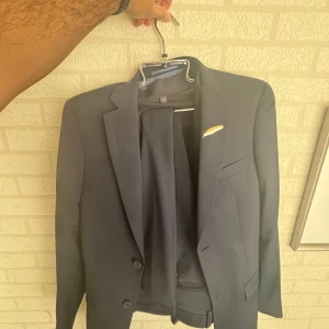 Kostym/studenten - Hej. Säljer min kostym som jag då har haft på studenten. Köpt från dressman och inkluderar 2 kostymbyxor, 1 kavaj, och 2 skjortor. Kostymen är bra skick, dock är den lite smutsig och dammig men den har inga skador eller hål! Nypris på allting ligger på ca 5500kr. Men jag säljer allting idag för endast 1400kr!  Kavajen är i storlek 46=S. Bägge skjortor storlek 37/38=S. Svarta kostymbyxorna är i storlek 30/30. Och marinblåa storlek 31/30. 
