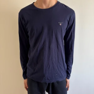 Mörkblå långärmad tröja från GANT - Säljer en stilren mörkblå långärmad tröja från GANT i bomull. Tröjan har rund halsringning och en liten broderad GANT-logga på bröstet. Passar perfekt till vardags för en enkel och klassisk look. Skriv kring mer information😀