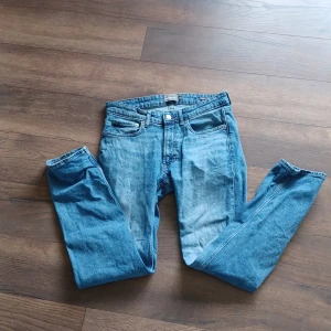 Blå jeansbyxor från Dressmann - Klassiska blå jeansbyxor från Dressmann med fem fickor och raka ben. Byxorna har normal passform och stängs med dragkedja och knapp. Perfekta för en avslappnad stil och funkar året runt. Ordinarie pris 849..