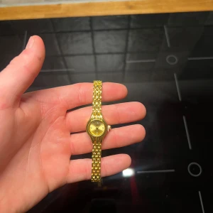 Guldklocka  - Helt oanvänd klocka med justerbart armband och nytt batteri. Den är gjort av 100% rostfrittstål. Armbandet justera du lätt hemma med hjälp av en nål. 