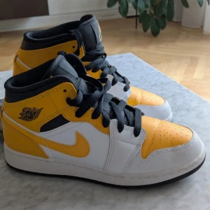 Nike Air Jordan 1 Mid gul och vit - Säljer ett par Nike Air Jordan 1 Mid i en snygg gul, vit och svart färgkombination. 