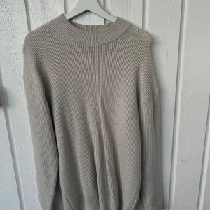 Beige stickad tröja från Pull&Bear - Säljer en stilren beige stickad tröja från Pull&Bear. Tröjan har rund halsringning och långa ärmar, perfekt för lager-på-lager. Enkel och snygg design som passar till det mesta.