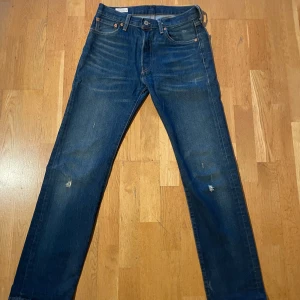 Levi's 501 jeans blå denim - Klassiska blå Levi's 501 jeans i denim med raka ben och femficksmodell. Byxorna har knappar i gylfen och tydliga Levi's-detaljer som röd etikett och läderpatch bak. Perfekta för en tidlös och avslappnad stil samt matchar med allt! 