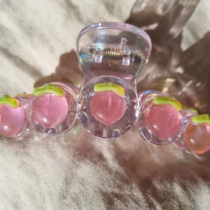 Hårklämma med persika  - Säljer en söt hårklämma. Passar bra för tjockt hår. Storlek 11cm långt 3,5cm bredd. 