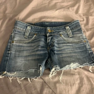Low waist Blå jeansshorts med fransar från Lee - Säljer ett par blå jeansshorts från Lee. Säljer dom då dom inte passar mig, har inte heller nån storlek på dessa men skulle säga xs. Jag får själv på mig dom men kan ej stänga dom i midjan och har själv storlek w26.