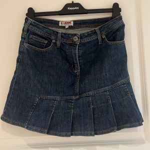 Jeanskjol med volang - Säljer en snygg jeanskjol från Kookai med volangdetalj nedtill. Kjolen har klassiska fickor fram och bak, samt markerade sömmar. Perfekt för dig som gillar denim och vill ha en kortkjol med lite extra stil. PRIS GÅR ATT DISKUTERA