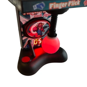 Finger Flick Mini Boxningsspel Mood Light - Säljer ett mini boxningsspel med LED-lampa som skiftar färg. Spelet har en digital poängräknare, svart bas och en boxningsboll i plast. Perfekt som rolig prydnad eller stressleksak till skrivbordet. Märkt med 'Finger Flick' och har en tecknad boxare på framsidan.