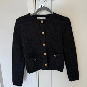 Svart/mörkgrå stickad kofta från Zara💖 - Mysig svart stickad kofta från Zara med rund halsringning och dekorativa guldknappar framtill. Två fickor framtill och långärmad modell. Perfekt för lager-på-lager och enkel att styla.