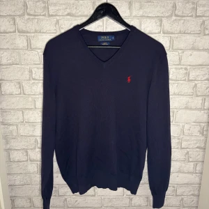 Ralph Lauren v-ringad tröja - Mörkblå v-ringad tröja från Ralph Lauren i merinoull, slim fit, storlek M. Väldigt bra skick, knappt använd och väl omhändertagen. Klassisk och stilren med röd logga. Hör av dig vid intresse🙌