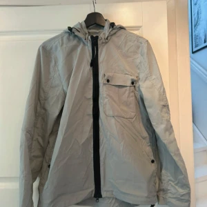 Ljusgrå Goggle Jacket från C.P. Company - Säljer min C.P. Company jacka som är använd 1 gång den är i storlek (M)   Längd 70 bred 50 