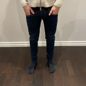 Mörkblå jeansbyxor - Snygga mörkblå jeansbyxor med slim passform. Byxorna har kontrasterande sömmar och en knappgylf. Perfekta för en stilren look. Priset är 499 men kan diskuteras.