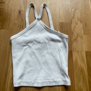 Vit ribbad linnetopp - Säljer en vit ribbad linnetopp med smala axelband och croppad passform. Perfekt för varma dagar eller som ett lager under en skjorta. Enkel och stilren design som passar till mycket.