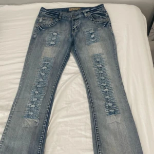 blå slitna jeans med pärldetaljer - säljer ett par blå jeans med slitningar och pärldetaljer längs benen även vid fickorna. byxorna är bootcut och helt oanvända 💕