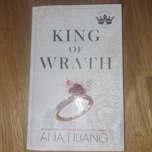 King of Wrath - En engelskspråkig roman av Ana Huang med titeln 'King of Wrath'. Omslaget är vitt med silvertext och en illustration av en ring med röd sten. Boken tillhör serien 'Kings of Sin' och handlar om kärlek, makt och familj.