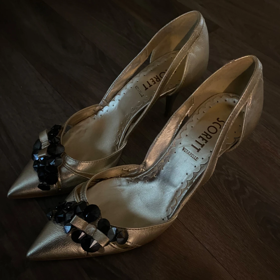 Guldiga pumps med svarta pärlor från Scorett