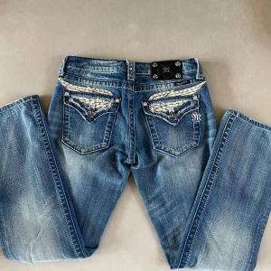 Blå bootcut jeans från Miss Me - Blå Miss Me Bootcut Jeans - Perfekta Vingar för Din Stil!  Midjemått höftsöm till höftsöm: Cirka 38cm. Letar du efter jeans som sticker ut och ger dig en unik look? Då är dessa Miss Me bootcut jeans något för dig! Med sina snygga detaljer och bekväma passform kommer de snabbt att bli en favorit i din garderob. Skick: Använda ett fåtal gånger, i jättebra skick!  📏 Storlek: W28. Kontakta mig om du är intresserad eller har frågor!😊