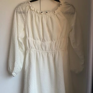 Vit långärmad klänning - Säljer en söt vit klänning från H&M med lång ärm och diskret prickigt mönster i tyget. Perfekt för sommaren!