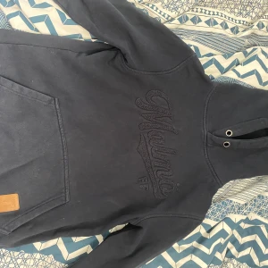 Mörkblå hoodie från Malmö FF - Säljer en mörkblå hoodie från Malmö FF med broderad logga och text på bröstet. Tröjan har huva med snörning och en stor magficka framtill. Strl S.      100kr