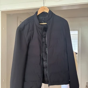 Svart pufferjacka från ZARA - Säljer en svart vår/sommar från ZARA med dragkedja framtill. Jackan har en enkel och stilren design med lång ärm och lätt vaddering som passar perfekt till sommar/vårkväll modellen är 183, 75kg.