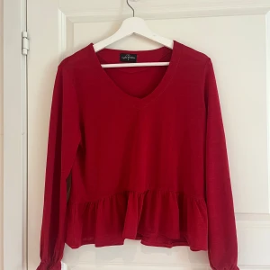 Röd volangtröja från Eight Sthlm - Säljer en röd långärmad tröja från Eight Sthlm med v-ringning och volangdetalj nedtill. Perfekt för dig som vill ha en enkel men ändå snygg topp till garderoben.PRIS GÅR ATT DISKUTERAS 