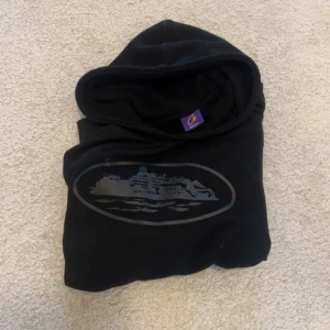 Corteiz hoodie, storlek S - Svart hoodie från Corteiz i storlek S med tryck av ett fartyg i grått och silver på bröstet. Klassisk huva och mjukt material, perfekt för en avslappnad stil. för fler bilder kom privat pris kan diskuteras 