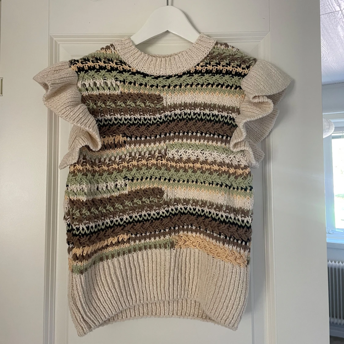 Stickad väst med volangärmar i beige och gröna toner