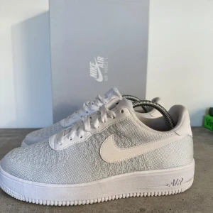 Nike Air Force 1 Flyknit 2.0 - Säljer ett par stilrena vita Nike Air Force 1 Flyknit 2.0. Skorna har en lätt och luftig design med klassisk snörning och en bekväm sula. Nypris 1499kr. Kommer med original box (använda fåtal gånger)