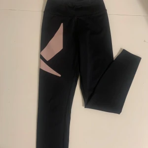 Träningsbyxor - Snygga svarta träningsbyxor från SOC med rosa geometriska detaljer på sidorna. De är högmidjade och har en tight passform, perfekta för träning eller en aktiv vardag. Materialet är stretchigt och bekvämt.