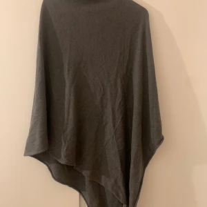 Grå poncho - Säljer en stilren grå poncho från lager 157. Perfekt för lager-på-lager under kyliga dagar. Den har en enkel design som gör den lätt att matcha med olika outfits. Ett måste för garderoben!