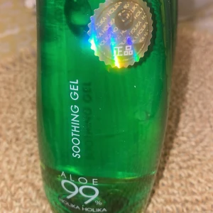 Aloe Soothing Gel från Holika Holika - Aloe Soothing Gel med 99% aloe vera från Holika Holika. Perfekt för att lugna och återfukta huden. Kommer i en grön flaska med holografisk etikett.
