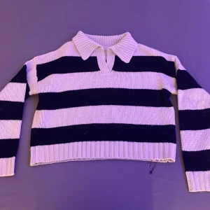 Randig stickad tröja med krage - Säljer en snygg randig stickad tröja med krage. Tröjan har breda ränder i svart och vit och långa ärmar. Perfekt för en stilren look.