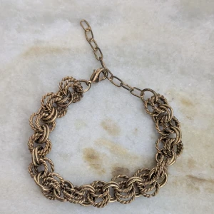 Guldigt armband med tvinnad design - Snyggt guldigt armband med en unik tvinnad design. Armbandet har en justerbar kedja för perfekt passform. Perfekt för att ge en elegant touch till din outfit.