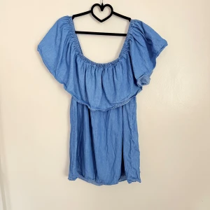 Blå offshoulder blus - Charmig blå offshoulder blus med volangdetaljer. Perfekt för en avslappnad sommarlook. Tillverkad i ett lätt och luftigt material som ger en skön känsla.