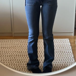 Blå bootcut jeans från Nelly - Snygga lågmidjade bootcut jeans i en medelblå nyans från Nelly. Perfekta för en avslappnad stil med en modern twist. De har en klassisk femficksdesign och en bekväm passform. Aldrig använda bara testade 