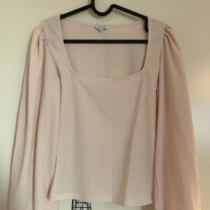 Beige långärmad topp från Bubbleroom - Stilren beige topp med långa ärmar och fyrkantig halsringning från Bubbleroom i storlek XS. Toppen har en lätt ribbad struktur som ger en fin detalj. Använd 1 gång. 