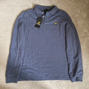 Blå pikétröja från Lyle & Scott - Säljer en stilren blå pikétröja från Lyle & Scott med lång ärm. Sicket är 10/10 aldrig använd. Finns det frågor är det bara att höra av sig😁