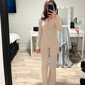 Beige ribbad set - Snygga beige ribbade byxor med hög midja och wide fit och beige ribbad tröja med knappar och en klassisk krage. Perfekta för en stilren look. XSS men passar XS 