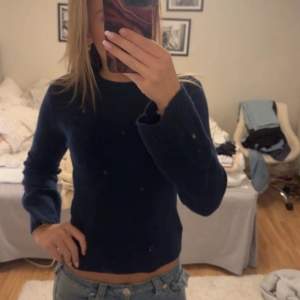 Säljer en mörkblå stickad tröja med rund hals och långa ärmar. Tröjan har en enkel design och är perfekt för kyligare dagar. Passar bra till jeans eller kjol för en avslappnad look.