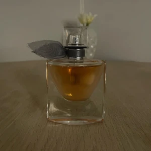 La Vie Est Belle by Lancome Eau De Parfum Intense for Women 30ml - En stilren parfymflaska med en fyrkantig form och en elegant svart rosett vid halsen. 
