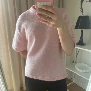 Rosa stickad tröja - Säljer en söt rosa stickad tröja med korta ärmar. Perfekt för en mysig dag hemma eller till jobbet eller skola. Tröjan har en enkel design med ribbstickade kanter. Som ny i skicket då jag använt den 2 gånger.
