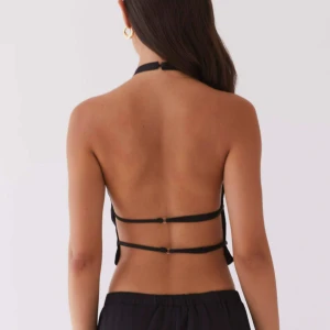 Svart halterneck topp - Snygg svart halterneck topp med öppen rygg. Perfekt för en stilren och modern look. Toppen är croppad och ger en elegant siluett. Köpt från peppermayo för 488kr 
