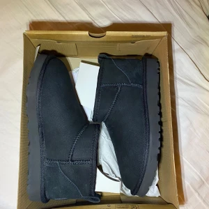 Svarta boots från UGG - Snygga svarta boots från UGG i mocka med en robust sula. Perfekta för kyligare dagar med sin varma insida. Klassisk design med UGG-logga på hälen.