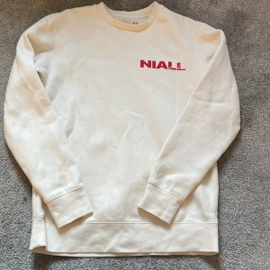 Beige sweatshirt med Niall Horan-tryck - Säljer en beige sweatshirt med tryck av Niall Horan i rött och svart. Tröjan säljs inte längre och har används minst 2 gånger vilket gör att den ser oanvänd ut. Köptes för 900kr. 