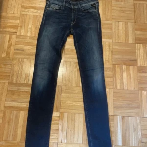 Mörkblå jeans från Replay - Snygga mörkblå jeans från Replay med en tight passform. De har en klassisk femficksdesign och en knappgylf. Perfekta för en stilren look.