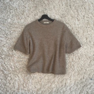 Beige stickad tröja från Gina Tricot - Säljer en mysig beige stickad tröja från Gina Tricot. Tröjan har korta ärmar och en rund halsringning. Inga defekter 💘